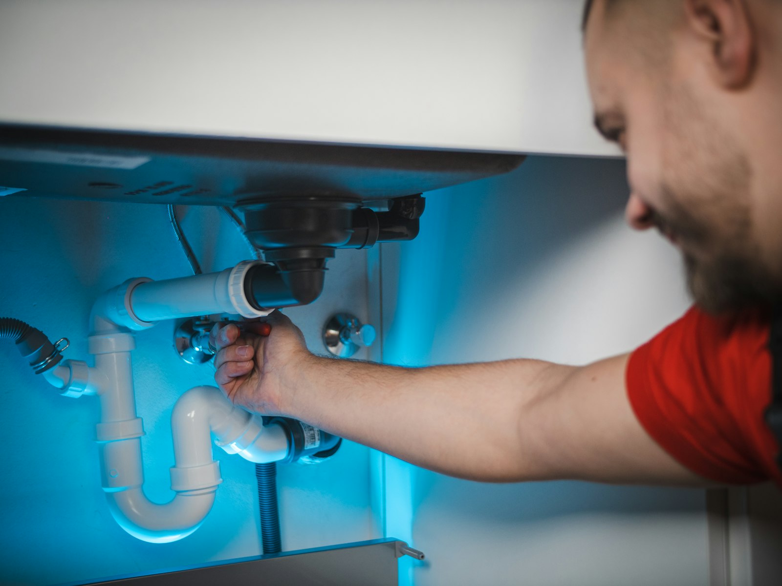 A plumber working under a kitchen sink