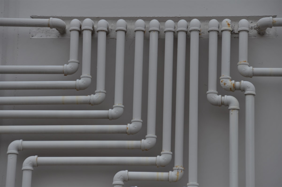 Clean white plumbing pipework installed against a wall