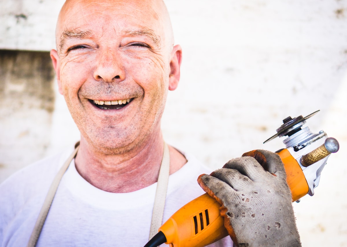 A tradesman smiling while holding a power tool